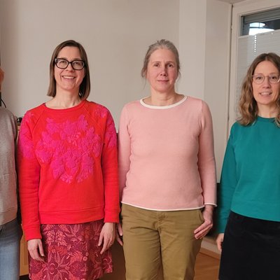 Vier Frauen posieren für ein Gruppenfoto. Sie stehen nebeneinander und lächeln in die Kamera.