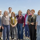 Zehn Personen posieren für ein Gruppenfoto. Sie stehen auf einer Terrasse in der Sonne.