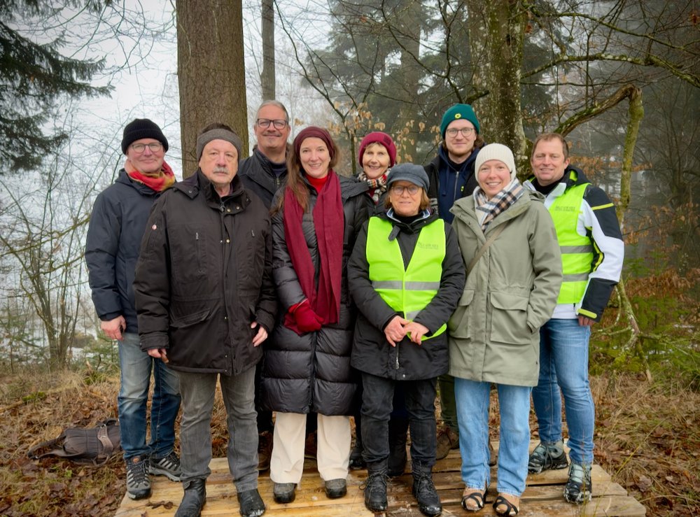 Grüne unterstützen Initiative „Wald vor Kies“ Eine Gruppe von neuen Personen posiert für ein Foto. Sie tragen Winterkleidung und stehen in einem Wald.