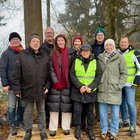 Eine Gruppe von neuen Personen posiert für ein Foto. Sie tragen Winterkleidung und stehen in einem Wald.