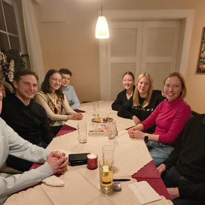 Acht Personen sitzen in einer Pizzeria an einem Tisch.