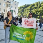 Zwei Frauen halten eine Fahne und ein Plakat. Auf dem Plakat steht "Es reicht. Das Leben bezahlbar machen. Niederbayern". Die Fahne ist grün und darauf steht "Bündnis 90 / Die Grünen".