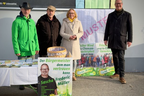 Vier Personen stehen hinter einem Infostand. Sie informieren zur Kommunalwahl 2026 in Bayern.