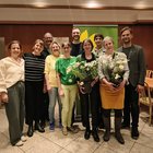 Zehn Personen posieren für ein Gruppenfoto. Zwei Personen halten Blumen in der Hand.