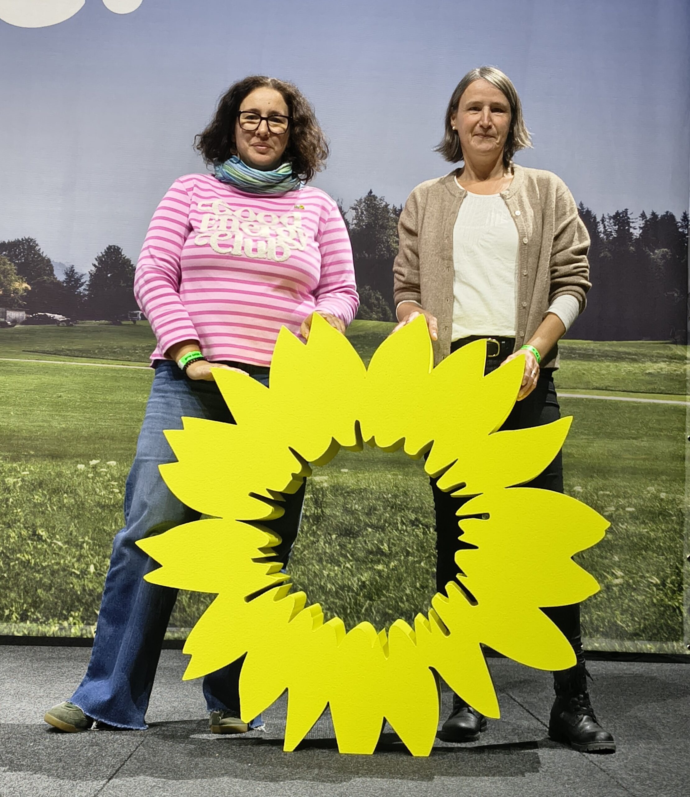 Zwei Frauen stehen vor einer großen Sonnenblume.